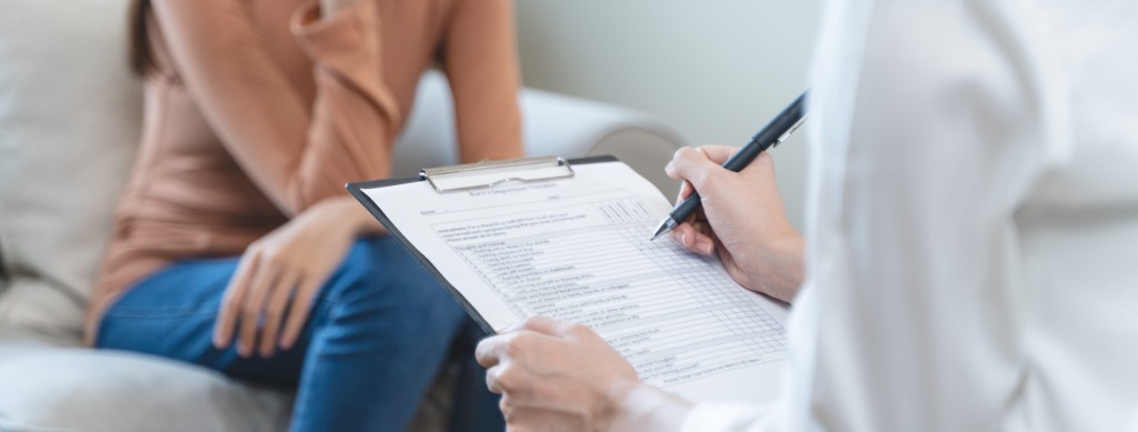 A clinician completing an assessment form during a consultation