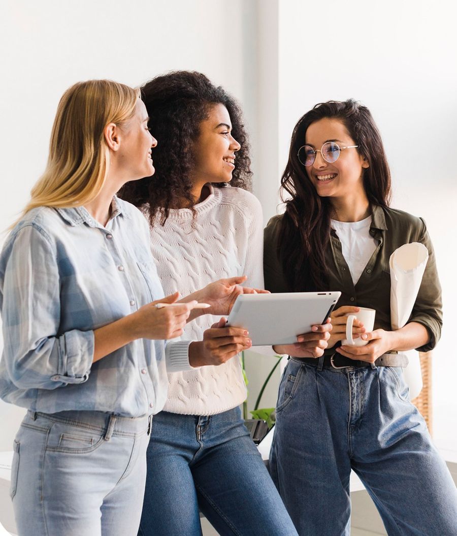 Three women talking together while looking at a tablet